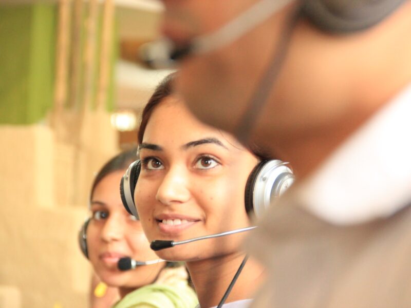 woman in black headphones holding black and silver headphones