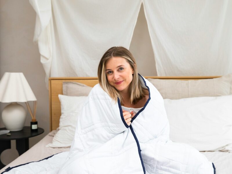 a woman sitting on a bed wrapped in a blanket