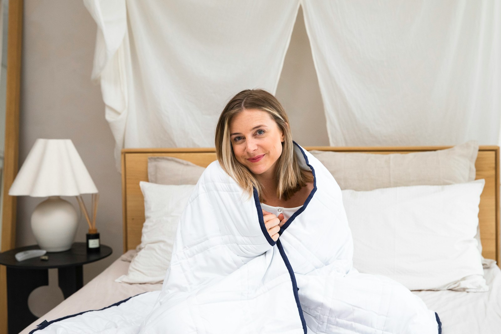 a woman sitting on a bed wrapped in a blanket