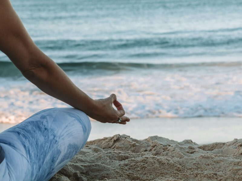 person in blue shorts sitting on beach shore during daytime