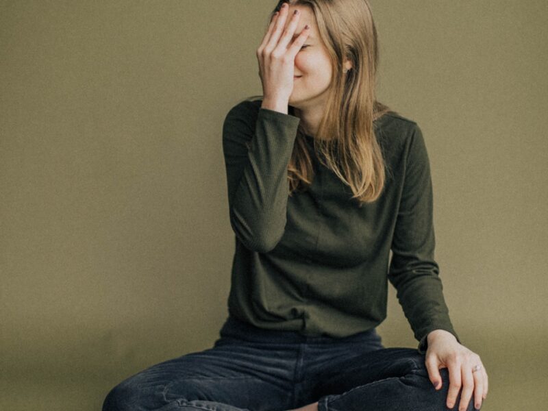 woman in black long sleeve shirt and blue denim jeans sitting on brown wooden chair