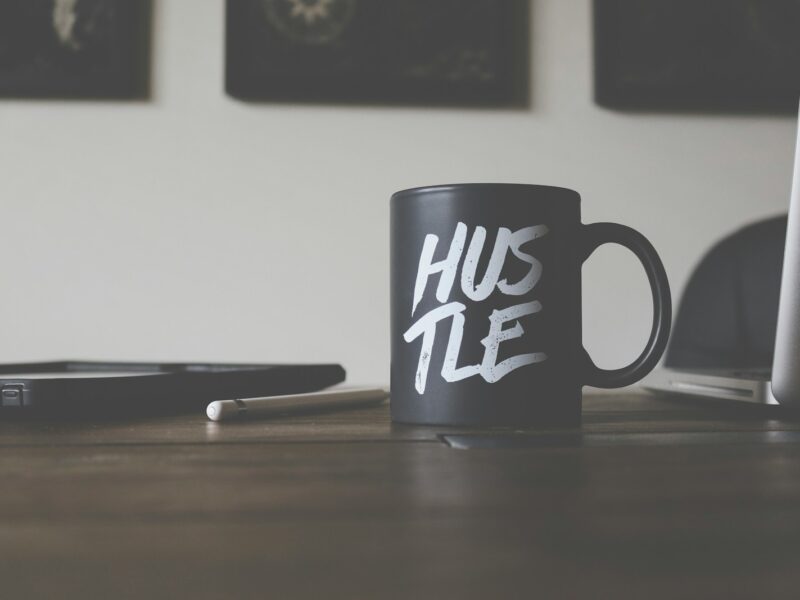 black and white Hustle-printed ceramic mug on table