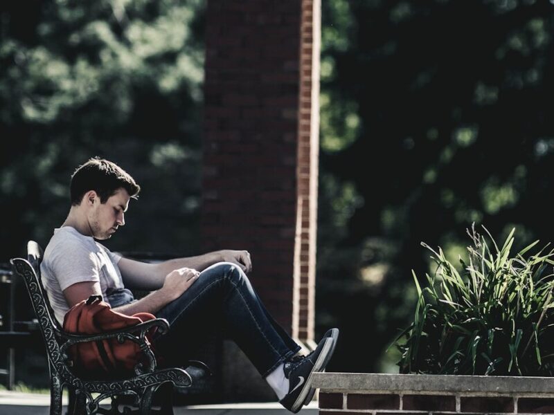 man wearing gray crew-neck t-shirt sitting on black metal bench