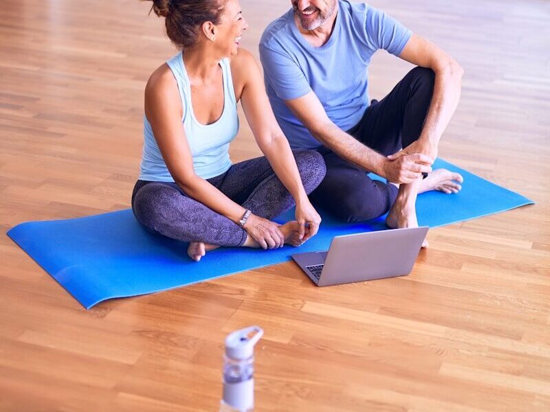 man in white tank top and gray pants sitting on blue yoga mat